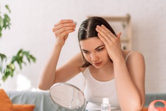 Femme regardant dans un miroir en appliquant de l'huile sur ses cheveux