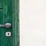 green wooden door beside white wall