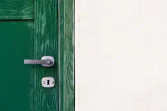 green wooden door beside white wall