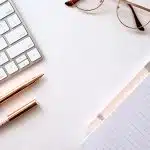 pen near black lined paper and eyeglasses